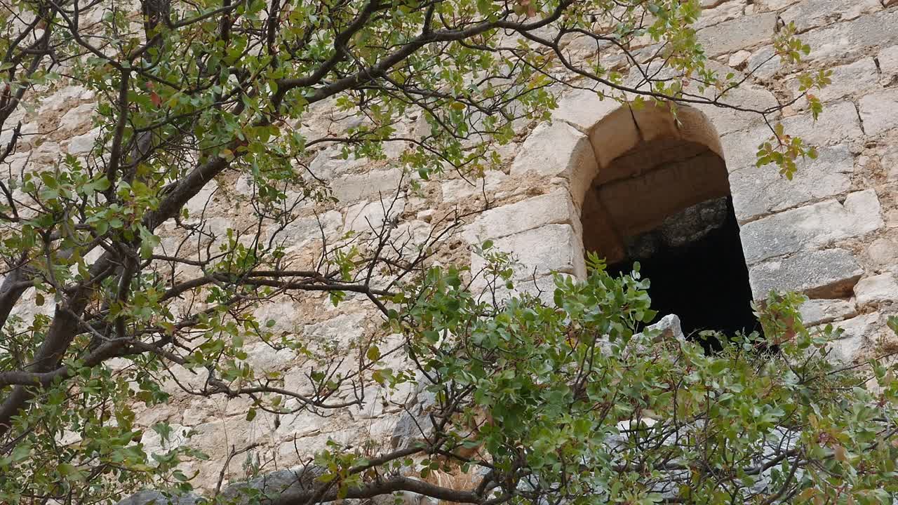 Window or arrow slit with a semicircular arch in the stone wall of Otiñar Castle, Jaén, Andalusia