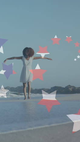 animation of stars and american flag over african american woman raising hands at beach