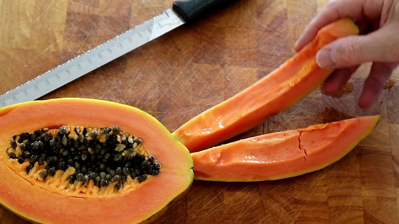 quitar rodajas de papaya roja de la tabla de cortar