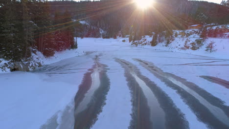 aerial: flying above frozen lake with hills around it. everything is covered with snow