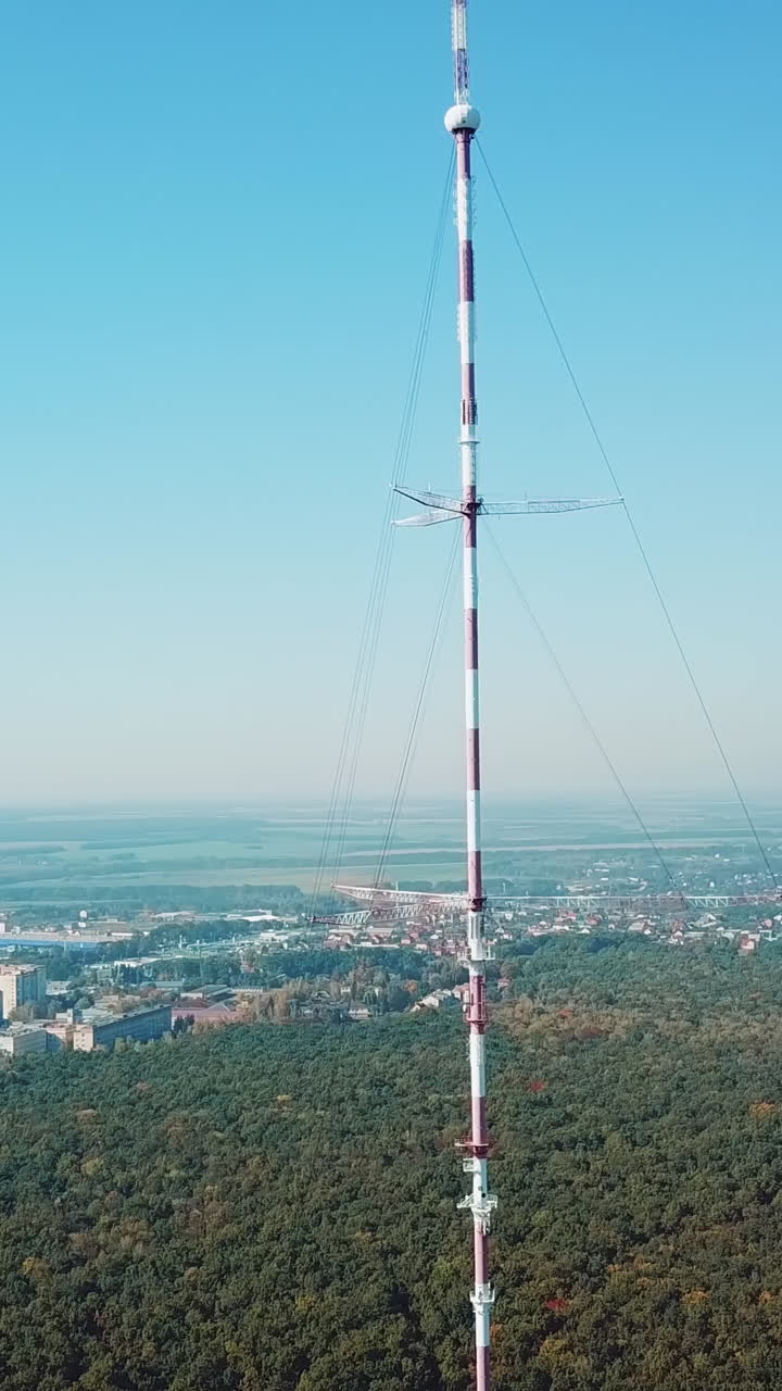 telecommunication antenna for television and radio broadcasting is located outside the city near the forest. Camera motion to left Vertical video