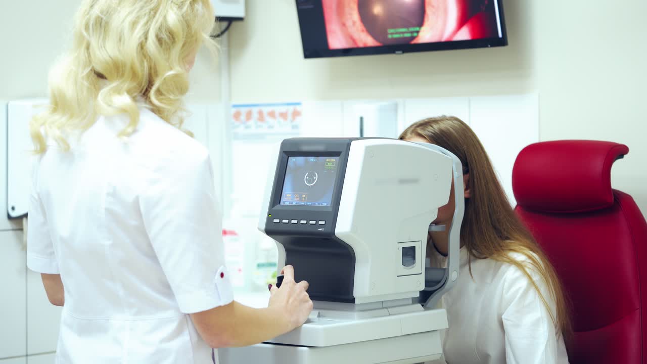 Doctor examining patient's eyes on modern device. Optometrist checks eyesight of a young woman with a refractometer in clinic.