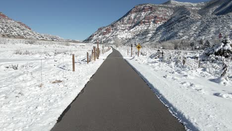 aerial footage along a bike path as it crosses a road and travels towards red mountains along interstate 70