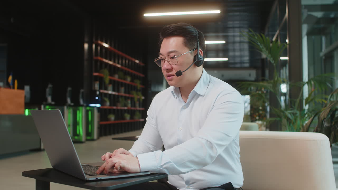 hombre de negocios maduro con computadora portátil usando auriculares servicio de apoyo hablando con el cliente en el vestíbulo de la oficina