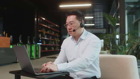 mature businessman with laptop wearing headset support service talking with client in office lobby