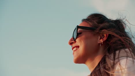 disparo en cámara lenta de una hermosa mujer con gafas de sol sonriendo y viendo el atardecer