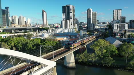 dos trenes que cruzan el río en el icónico puente ferroviario merivale de brisbane, suspendidos sobre el hermoso río brisbane, el extremo oeste, la orilla sur y la ciudad de brisbane visibles en esta impresionante toma de drones