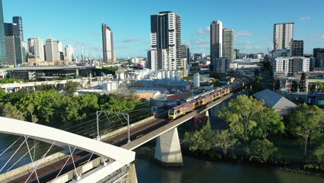 two trains crossing river on brisbane's iconic merivale railway bridge, suspended over the beautiful brisbane river, west end, south bank, and brisbane city visible in this stunning drone shot