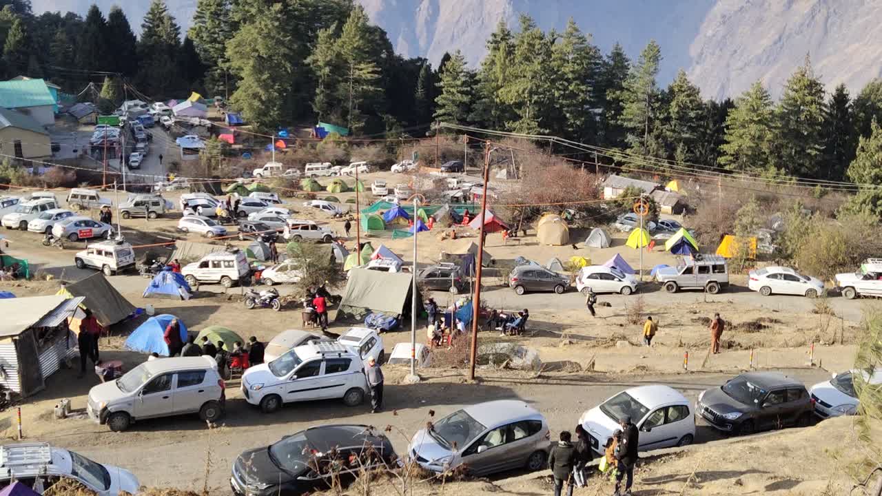 indian  view of vehicles, tents and people, camped in the auli lake