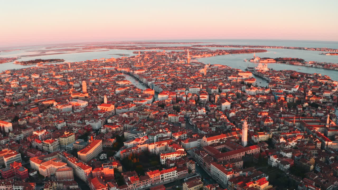 Ampla tomada aérea de drone em círculo sobre a cidade de Veneza sob a luz do pôr do sol.