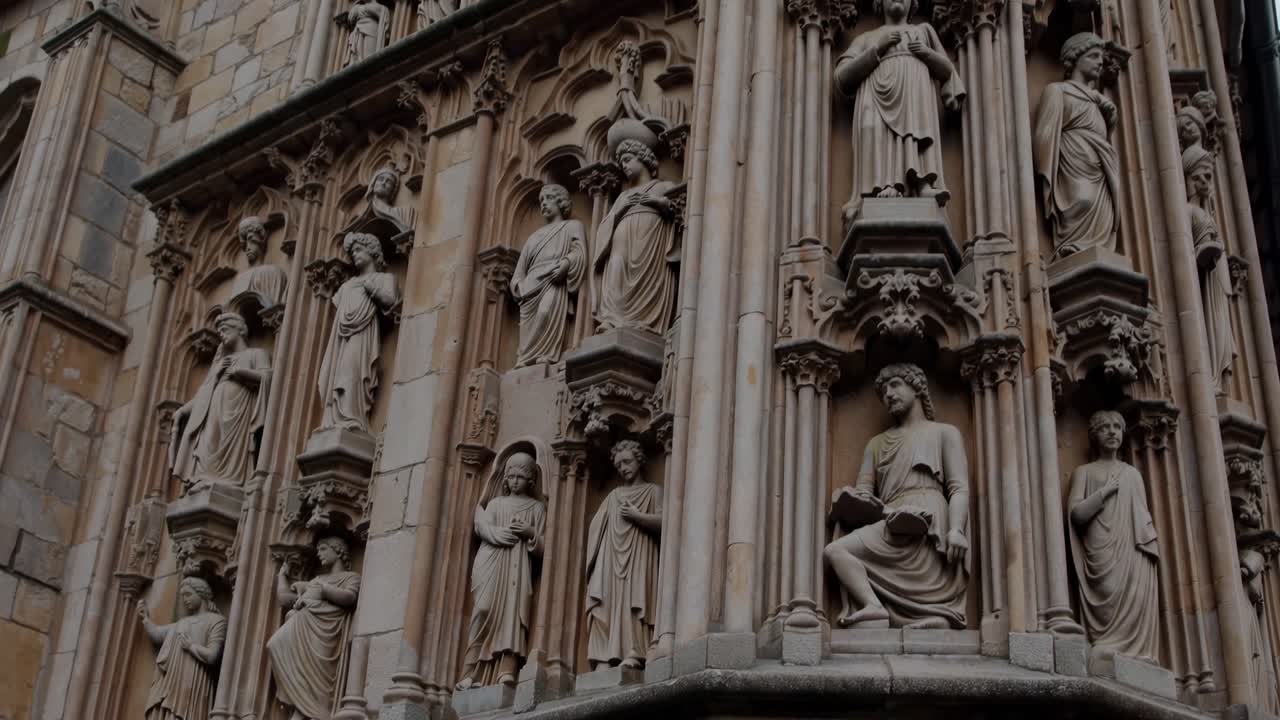 Un fermo immagine di un video di una strada medievale, che mostra edifici in pietra e torri.