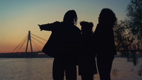 silhouette couple daughter enjoy river sunset lear sky. caring people together.