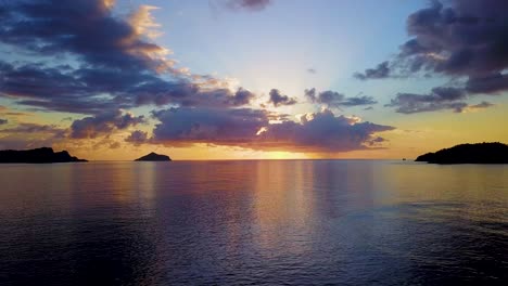 dramatic clouds during orange sunset with calm sea and islands, aerial shot