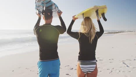 caucasian couple holding surfboards on the beach