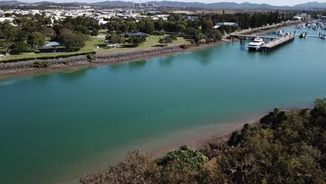 drone aerial pan up over park and blue water harbour on a sunny day