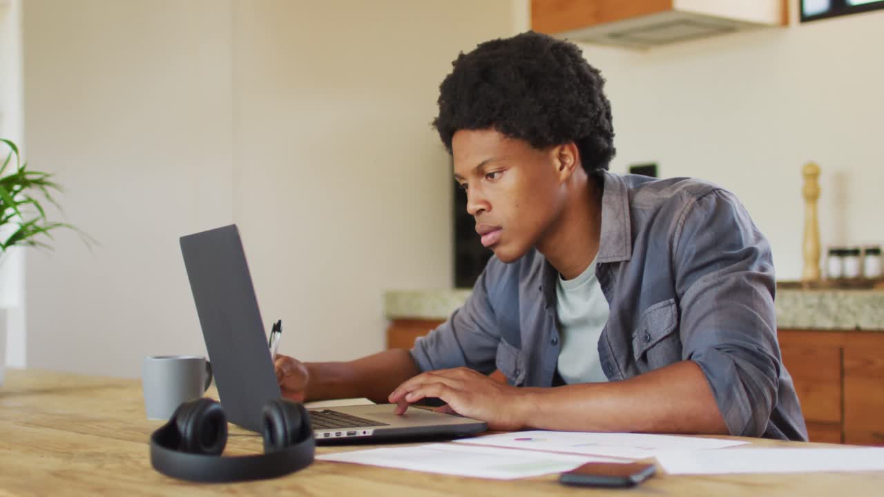 African american man working from home and using laptop