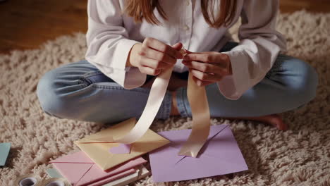 hands tying a ribbon on pastel envelopes for crafting