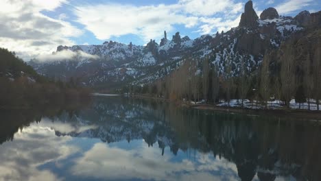 Die-Kamera-Bewegt-Sich-Langsam-über-Einen-Gespiegelten-Fluss,-Der-Von-Felsigen-Bergen-Umgeben-Ist,-Während-Die-Sonne-Untergeht