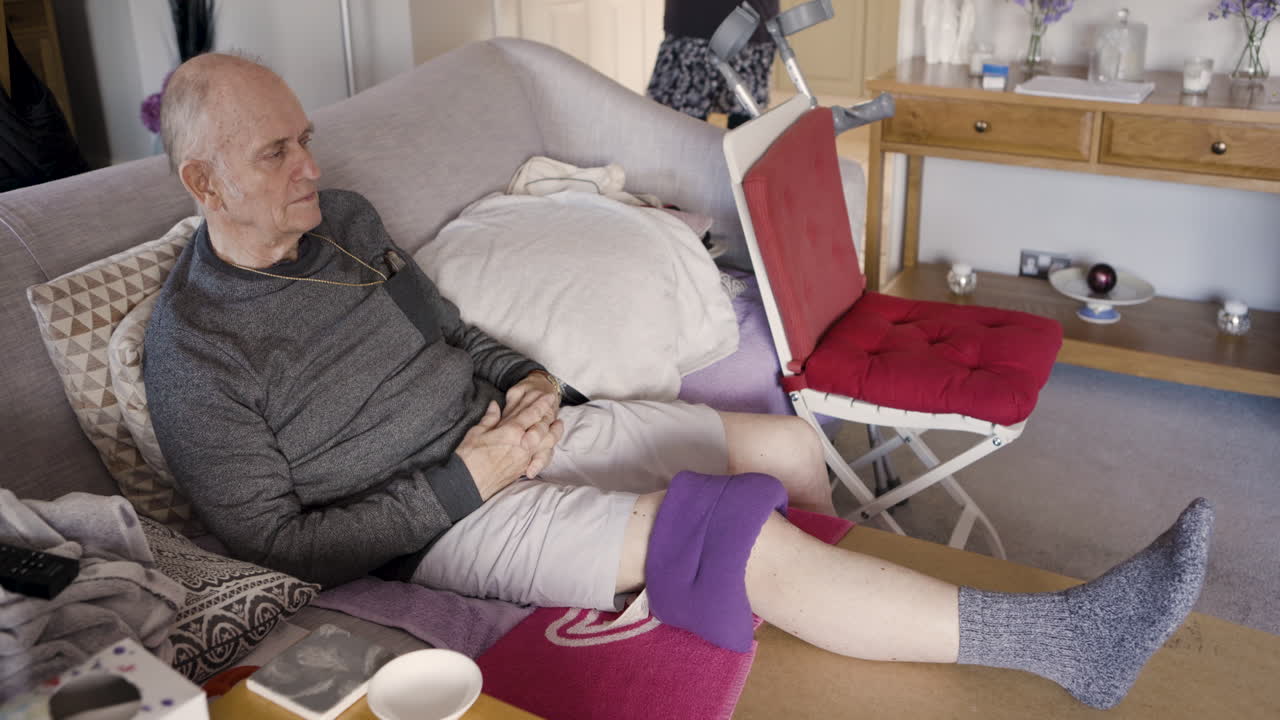 Elderly man resting at home with knee ice pack