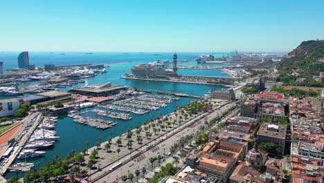 aerial view over square portal de la pau, and port vell marina and columbus monument during a sunny day in barcelona, catalonia, spain