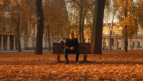 man sitting alone on a park bench in autumn