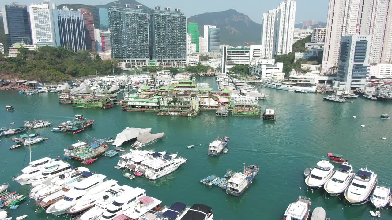Hong Kong marina and Typhoon shelter with skyscrapers and hundreds of small boats on a clear Summer day, Aerial pull up view.