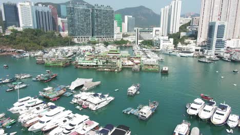 hong kong marina and typhoon shelter with skyscrapers and hundreds of small boats on a clear summer day, aerial pull up view.