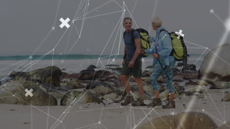 pareja de ancianos caucásicos caminando por el mar, sobre una red de conexiones en movimiento