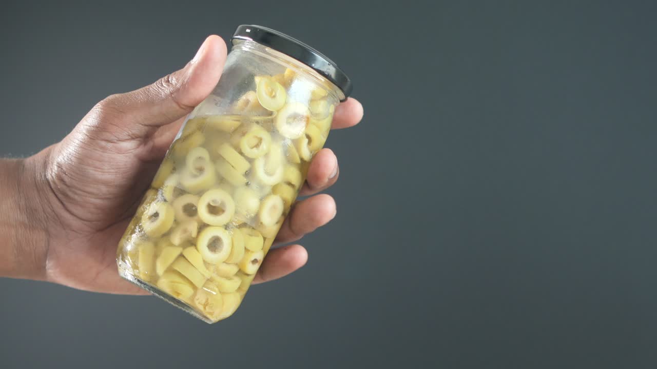 초록색 올리브 의 항아리 를 들고 있는 손