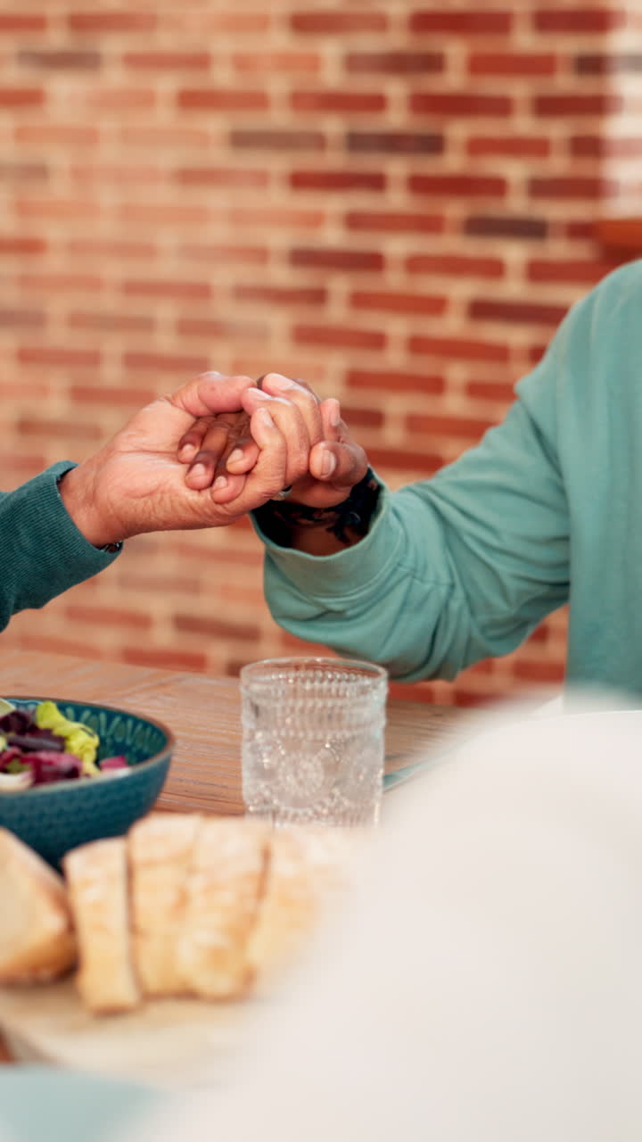 Close-Up of Two People Holding Hands and Praying at a Table