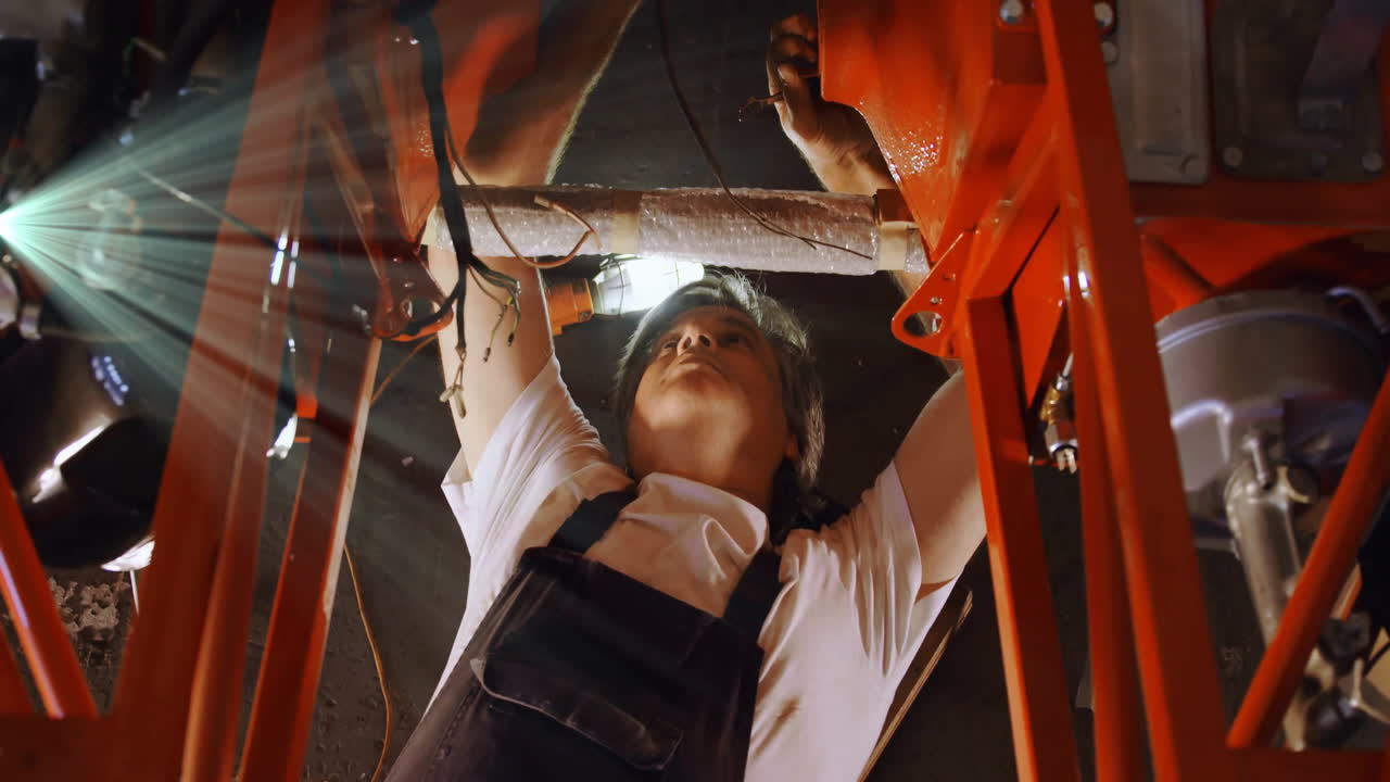 Technician tightening bolts under red steel beams, displaying animated tech data icons and charts