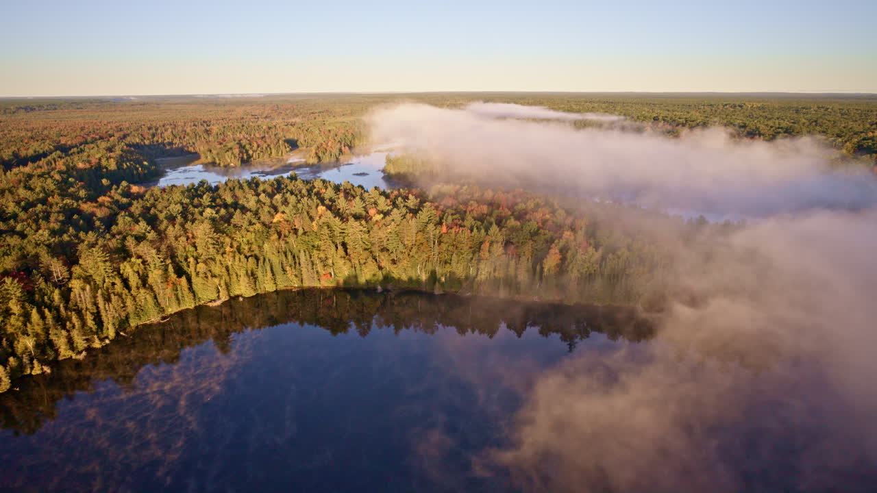 Cinematic aerial glide over misty water at dawn