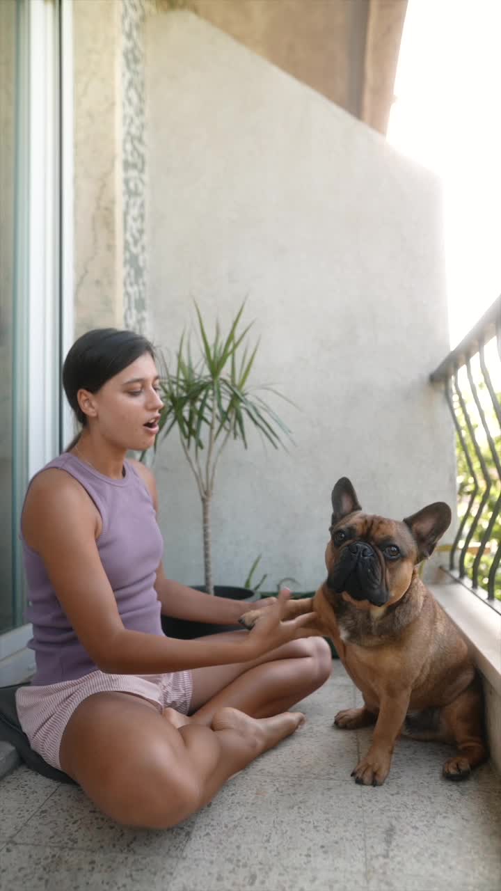 Woman and her French bulldog on a balcony