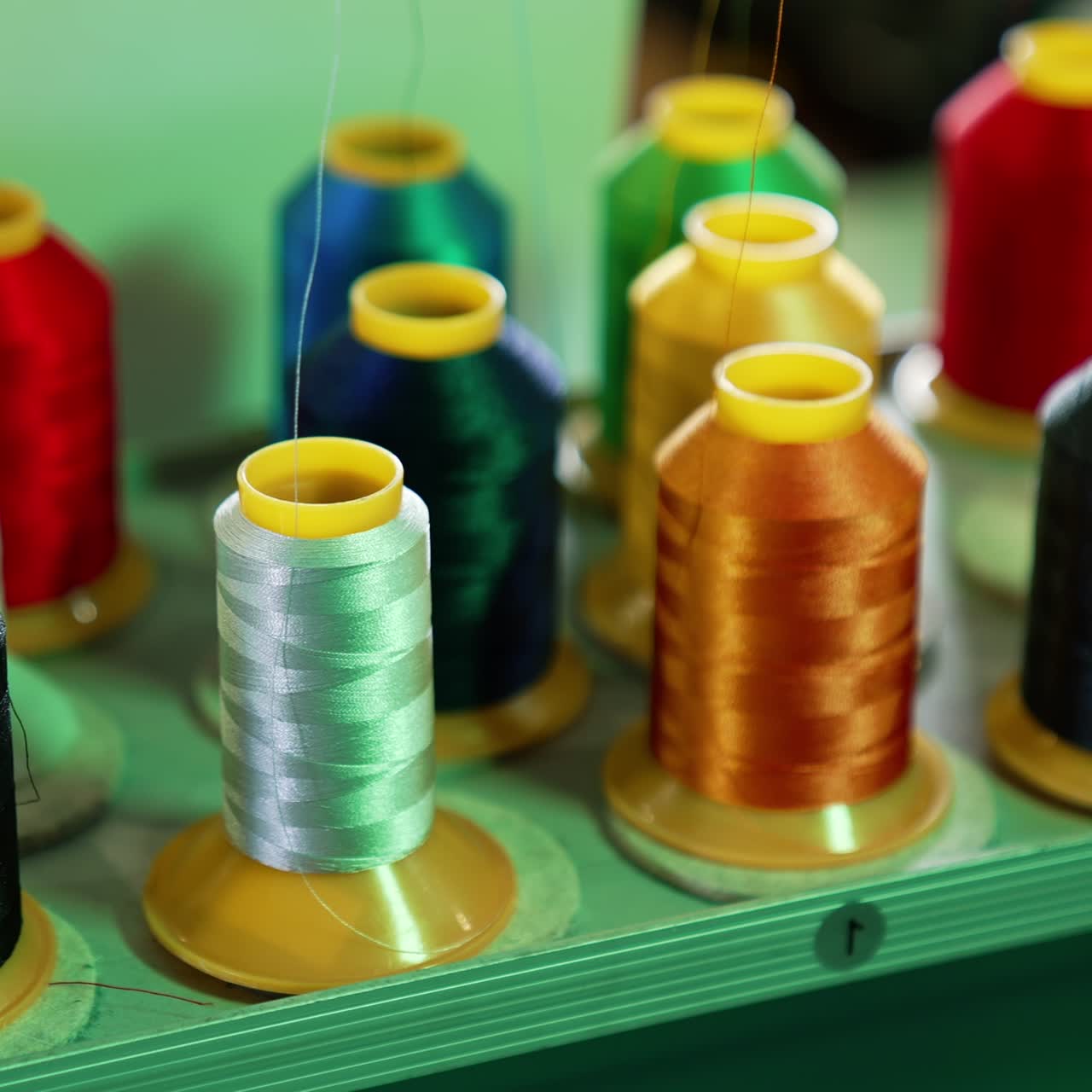 Bright threads in spools for tailor. Colorful spools with threads for sewing industry. Different colors of threads on the table. Handicraft