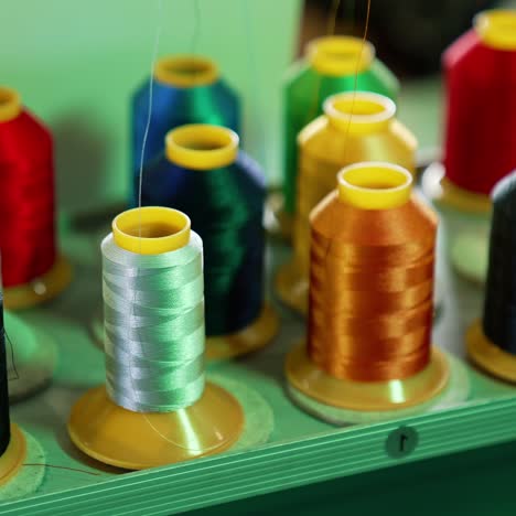 bright threads in spools for tailor. colorful spools with threads for sewing industry. different colors of threads on the table. handicraft