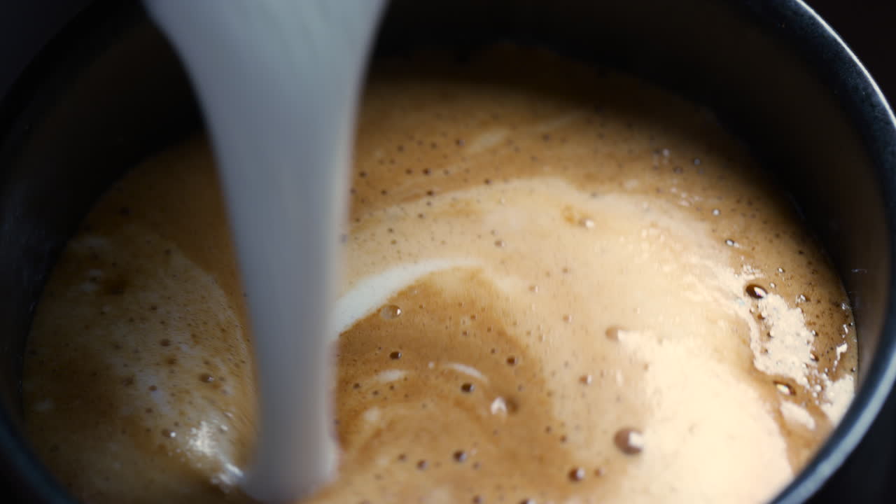 Milk is poured into a cup of coffee
