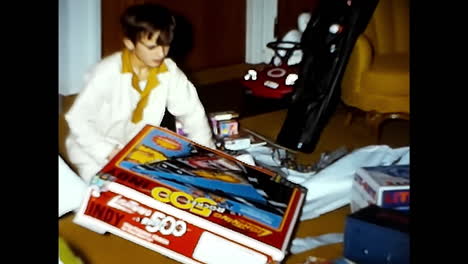 young boy sitting next to bed. circa usa - 1970s: a young boy sits on the floor beside a bed in a 1970s video archive from the usa.
