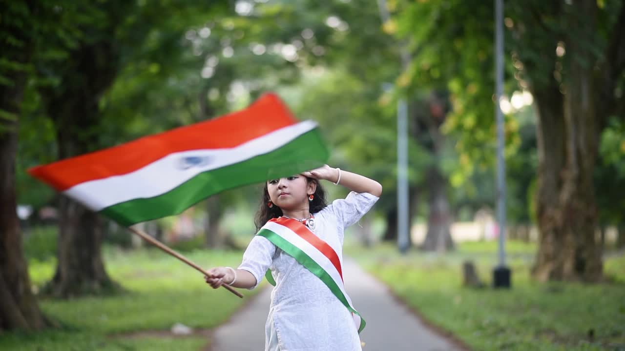 Una simpatica bambina indiana festeggia il Giorno dell'Indipendenza e della Repubblica indiana sventolando una bandiera tricolore dell'India al rallentatore.