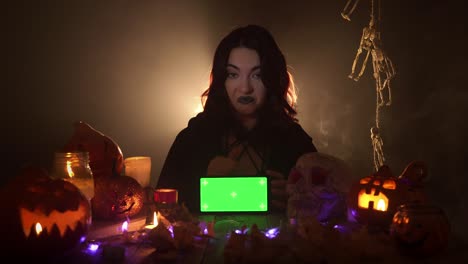 witch recommends a mobile with chroma key sitting among halloween decorations