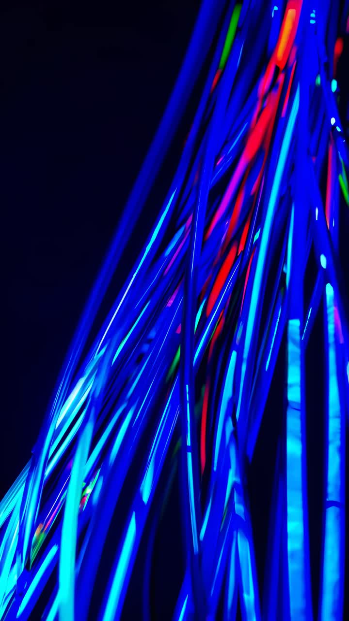 Dynamic close-up video of glowing neon wires in blue and red, captured from a low angle