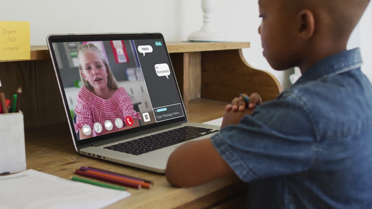 Schoolboy using laptop for online lesson at home, with his colleague and web chat on screen