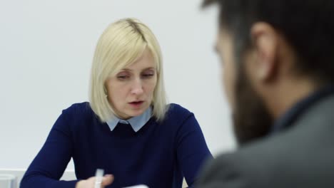 una mujer de negocios rubia hablando en una reunión de oficina.