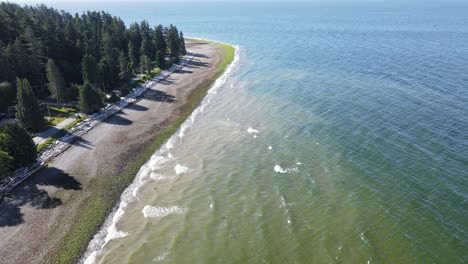 aerial fly over footage of bonniebrook beach in gibsons, british columbia on a sunny morning