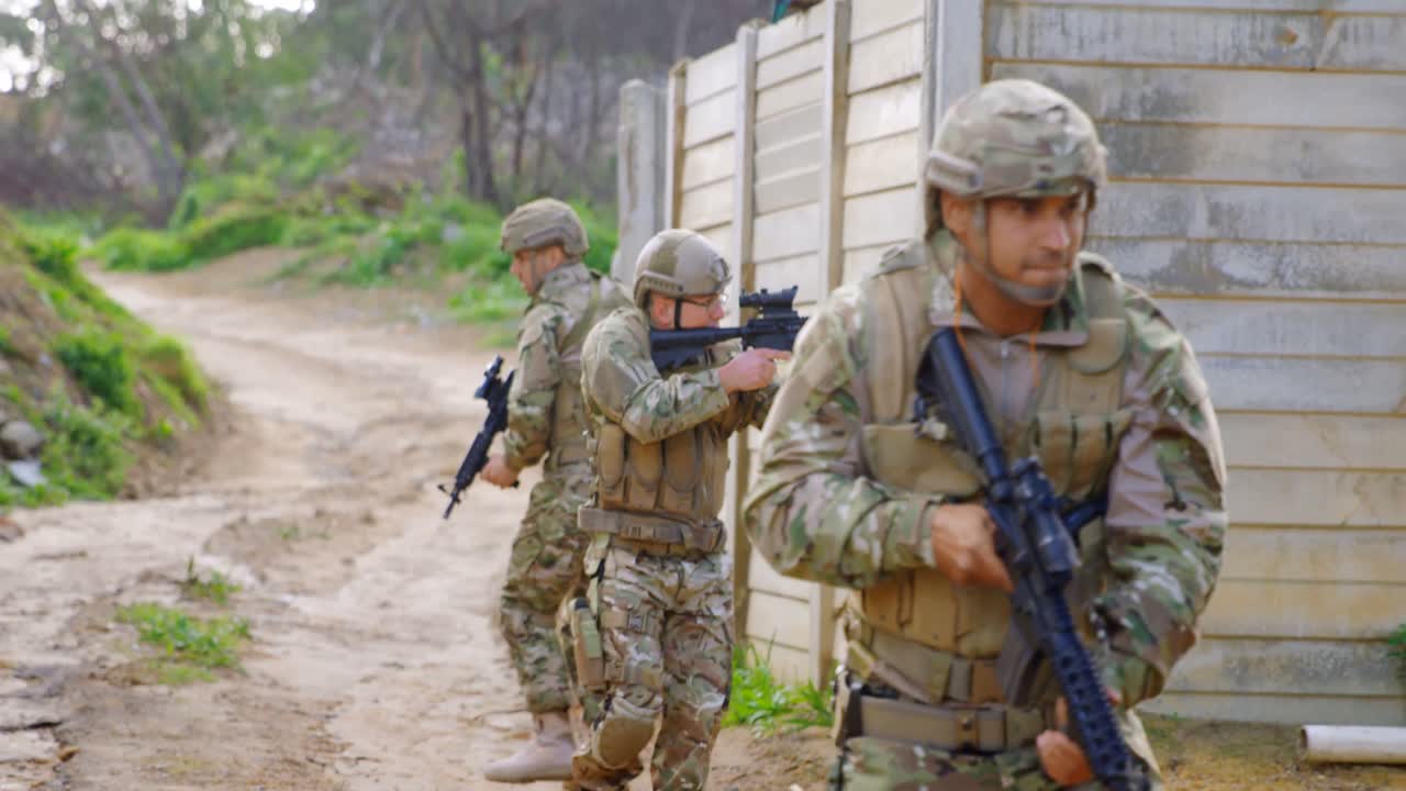vista frontal de los soldados militares caucásicos entrenando con rifles en los campos durante el entrenamiento militar 4k