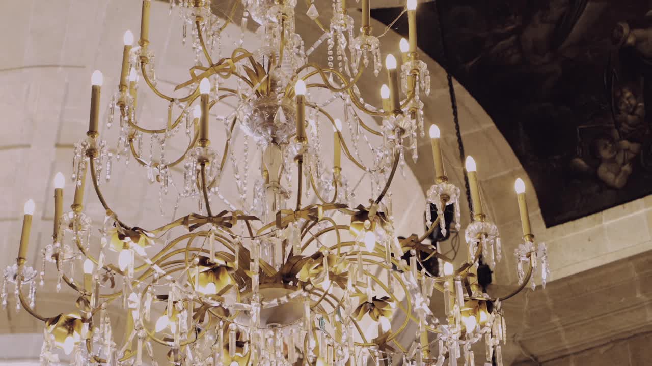 Elegant crystal chandelier with gold accents and warm candle lights in historic setting