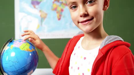 Schoolgirl-looking-at-globe-in-classroom-at-school