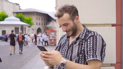 Junger-Mann-Schaut-Draußen-Auf-Der-Straße-Auf-Das-Telefon.