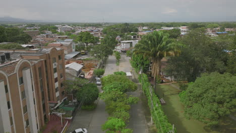 aerial footage following a box truck driving down a tree covered street in jamundí, colombia