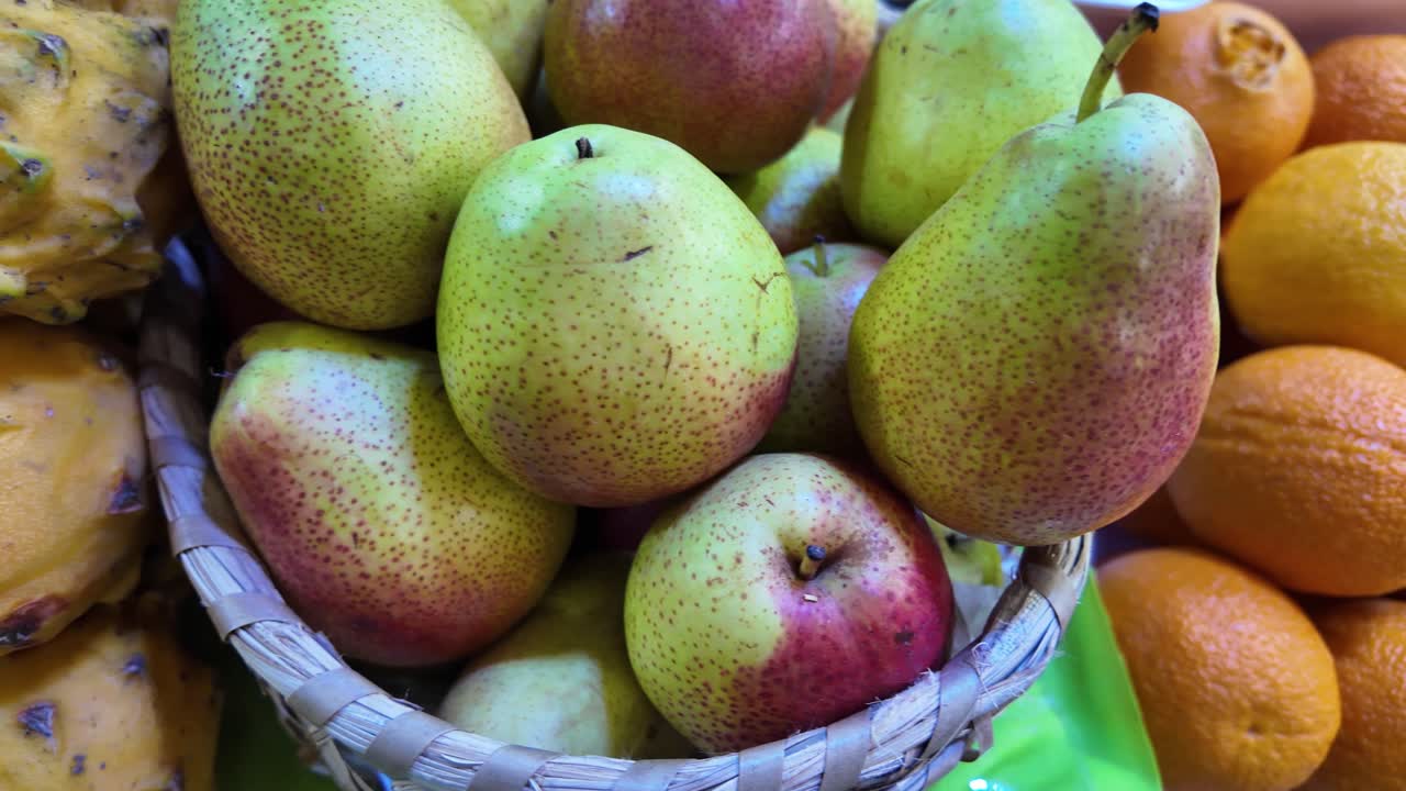 Primo piano di frutta colorata in un mercato alimentare, tra cui frutti del drago, pere e arance, che evidenzia i colori vivaci e i prodotti freschi