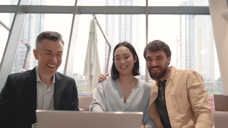 un equipo de trabajo mira la pantalla de la computadora portátil y celebra algunos resultados